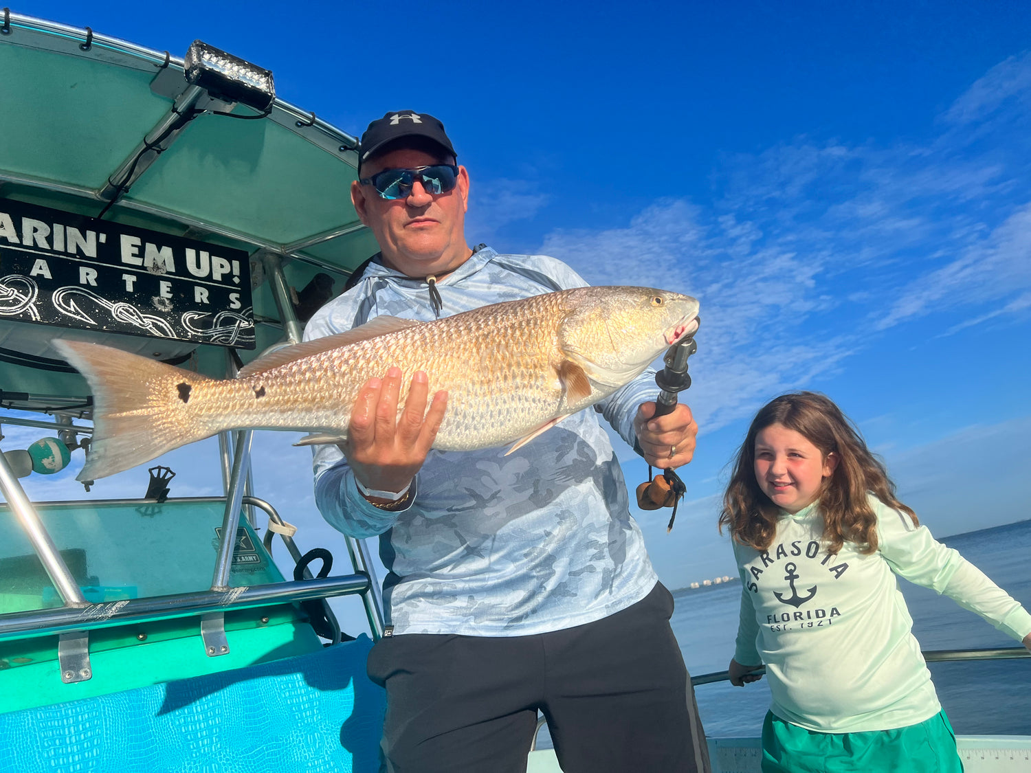 Dad and daughter holding a large Redfish near the Ringling Bridge